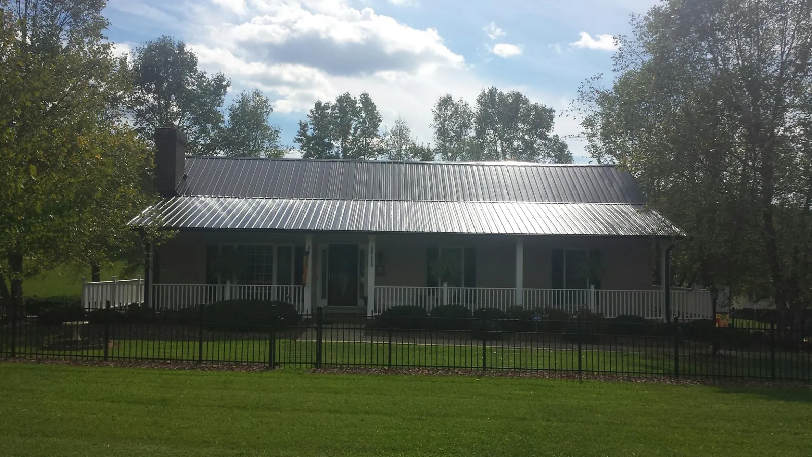 Gray metal roof on a brick ranch with a full width front porch — Gutter Guard Installation work by our crew in Pinehurst